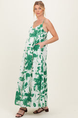 woman wearing a green and white floral maternity maxi dress with adjustable straps and pockets, displaying a baby bump