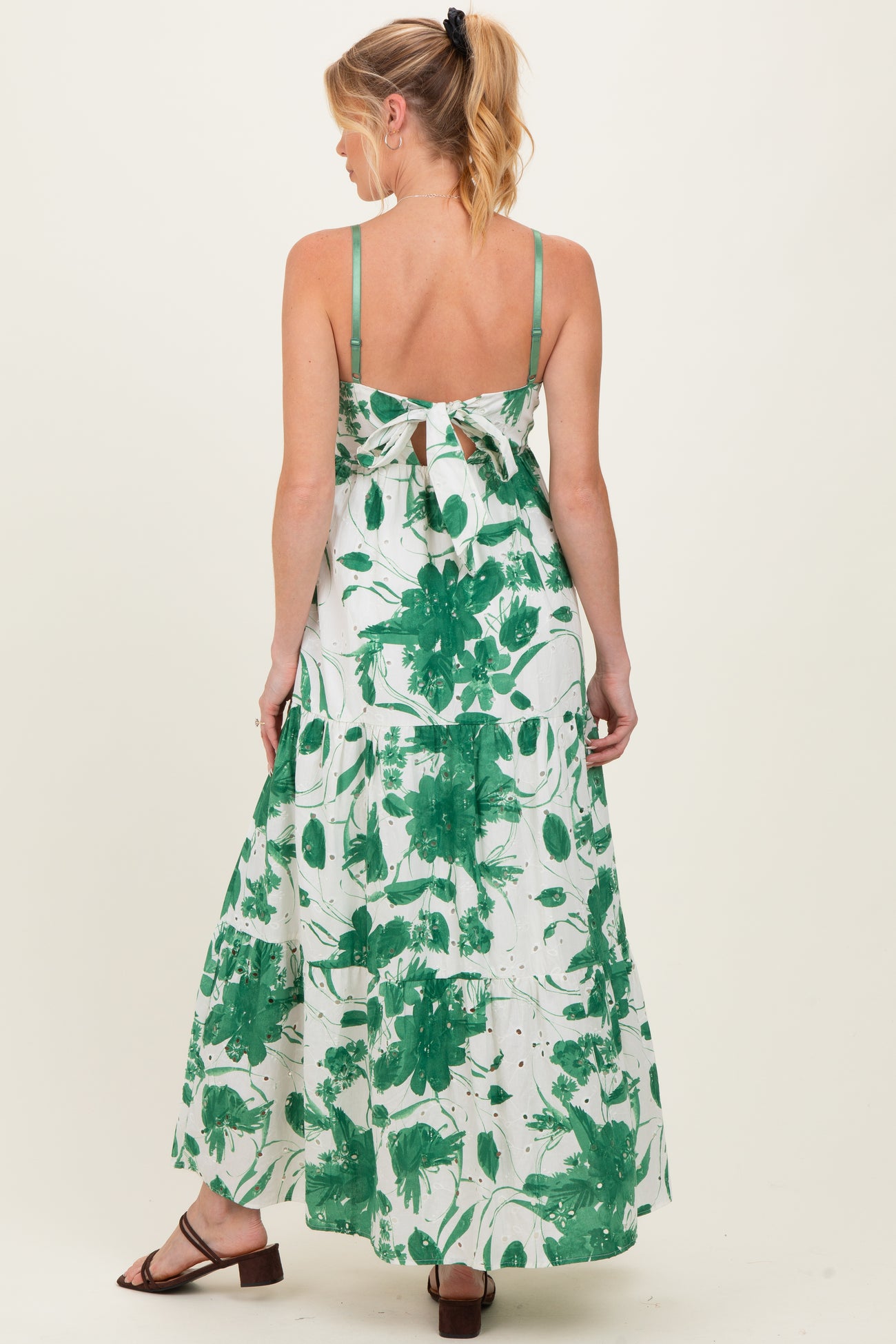 woman wearing a green floral print maternity maxi dress with a tie back detail, showcasing a baby bump