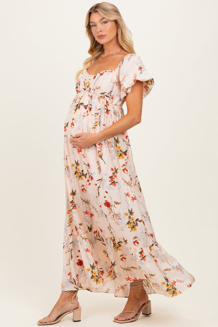 woman wearing a floral maternity maxi dress with short flutter sleeves and a visible baby bump
