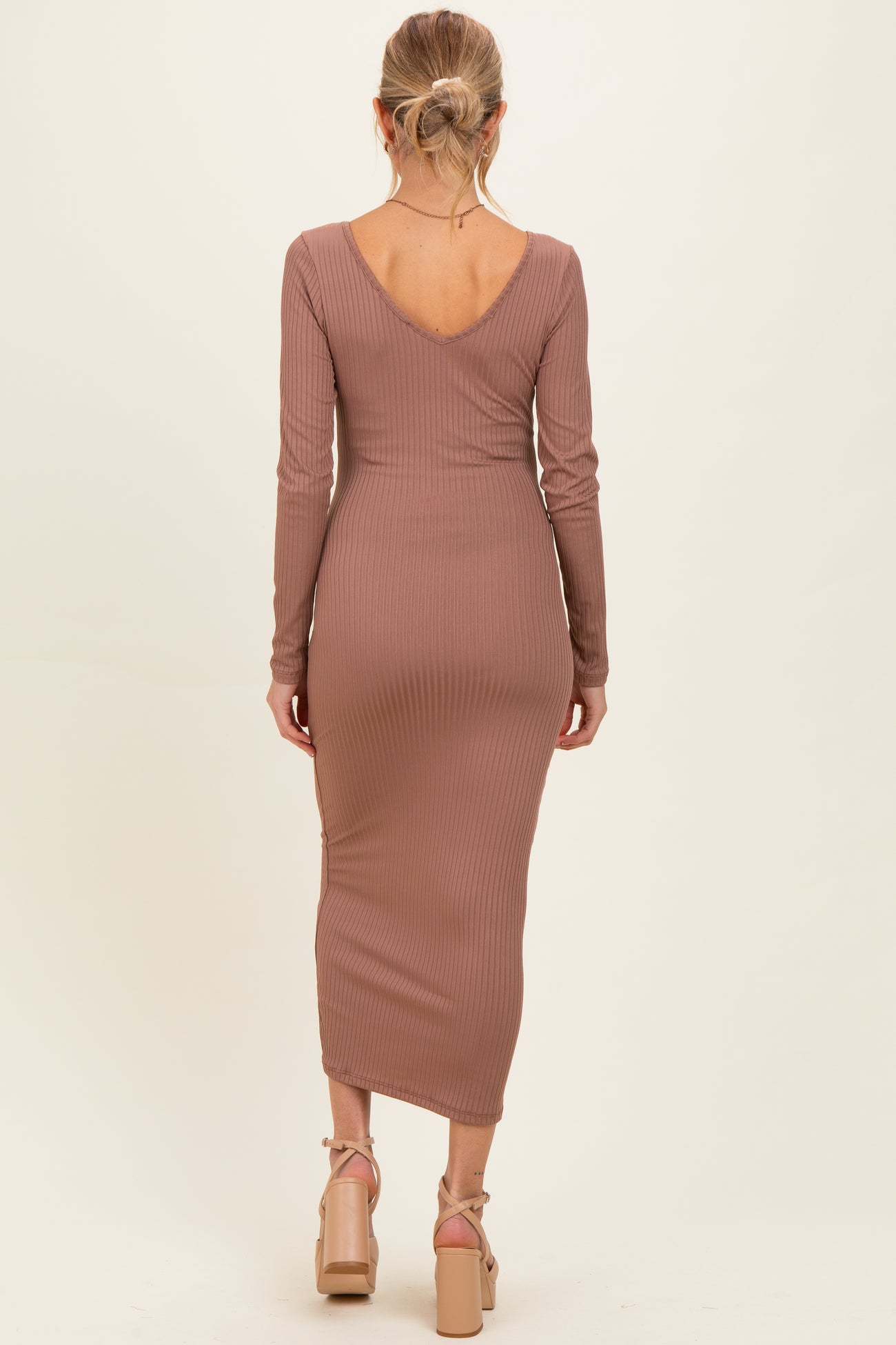 woman wearing a mauve long sleeve ribbed maternity dress with a v-back and a slim fit silhouette