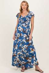 woman wearing a blue floral maternity maxi dress with short flutter sleeves and a gathered bodice, showcasing her baby bump