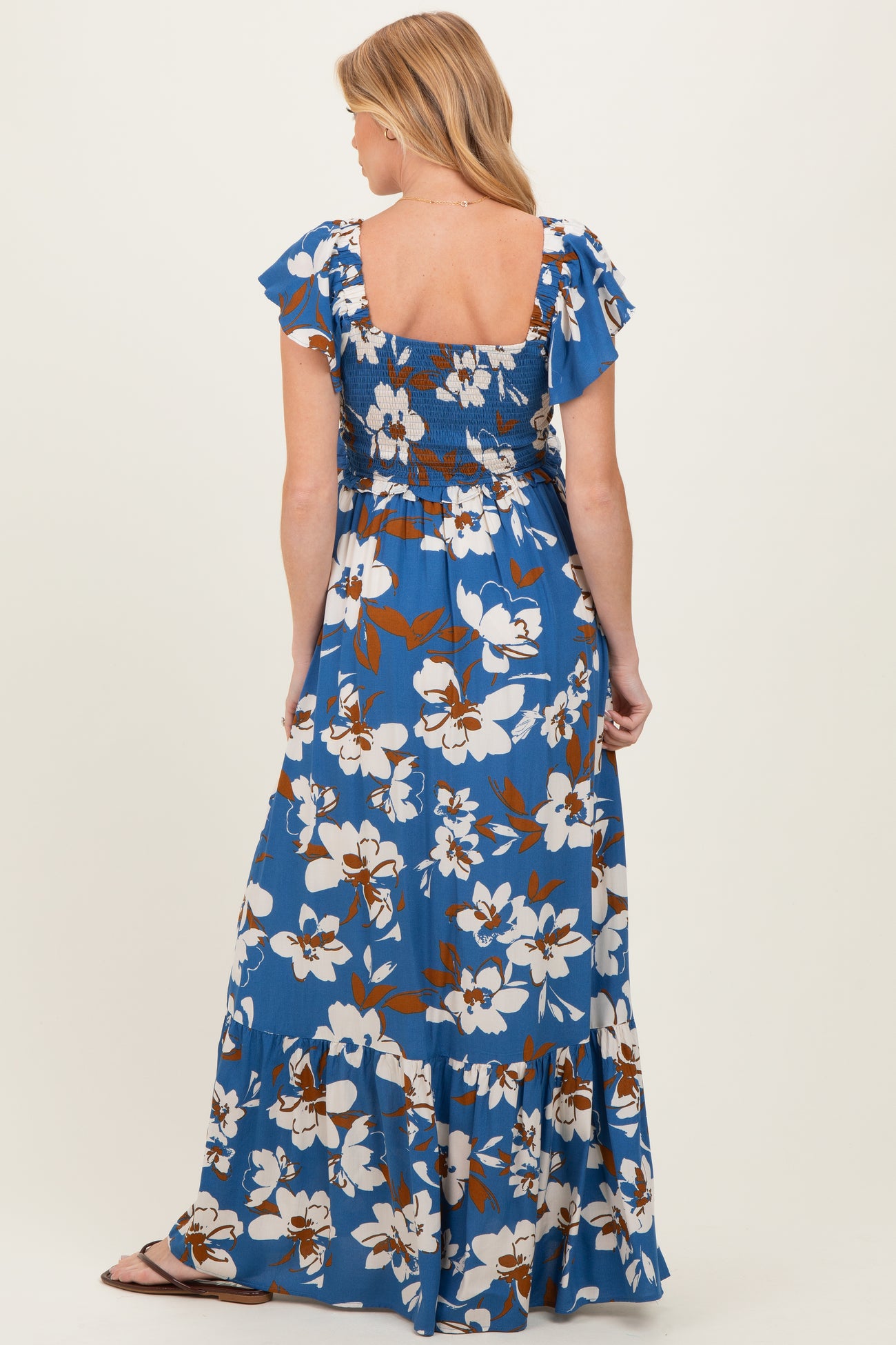 woman wearing a blue floral maternity maxi dress with ruffled sleeves and smocked back detail