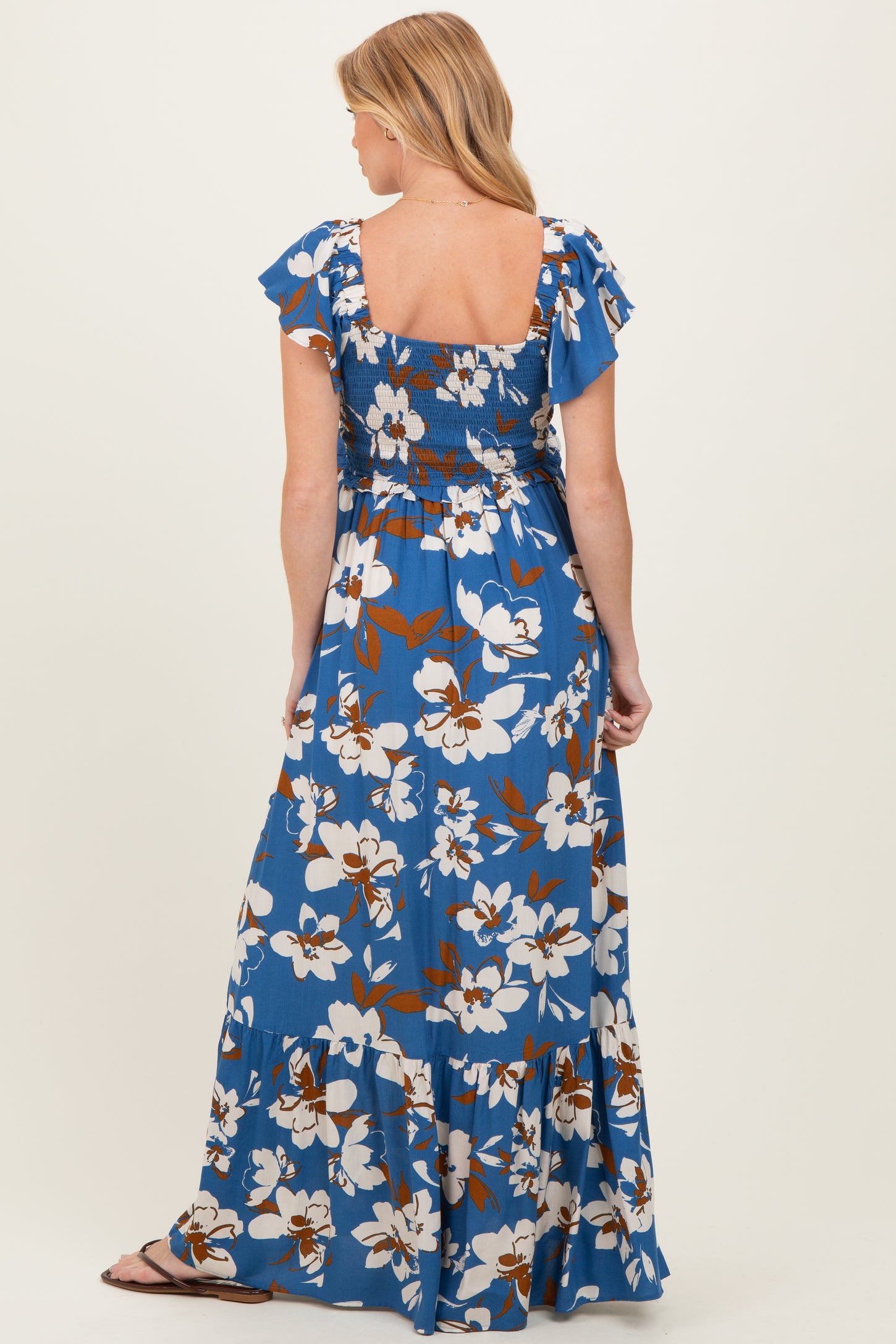 woman wearing a blue floral maternity maxi dress with ruffled sleeves and smocked back detail