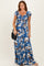 woman wearing a blue floral maxi dress with short sleeves and a gathered bodice, holding a black handbag