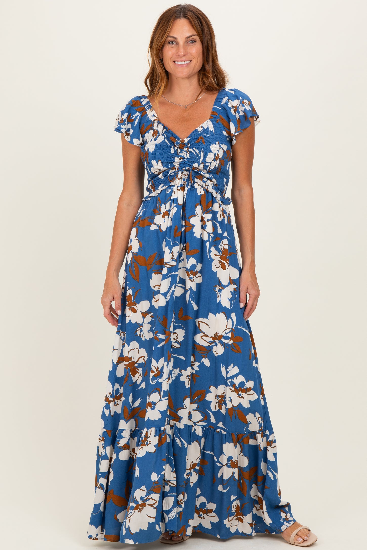woman wearing a blue floral maxi dress with short flutter sleeves and a cinched bodice