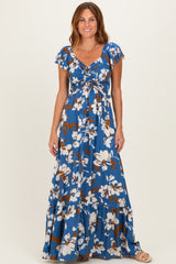 woman wearing a blue floral maxi dress with short flutter sleeves and a cinched bodice