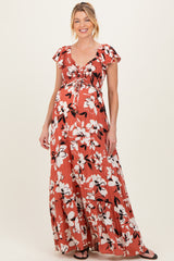 woman wearing a rust floral maxi maternity dress with a ruched bodice and short ruffled sleeves, showcasing her baby bump