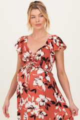 woman wearing a rust floral maternity dress with ruffled sleeves and a drawstring bodice, showing her baby bump