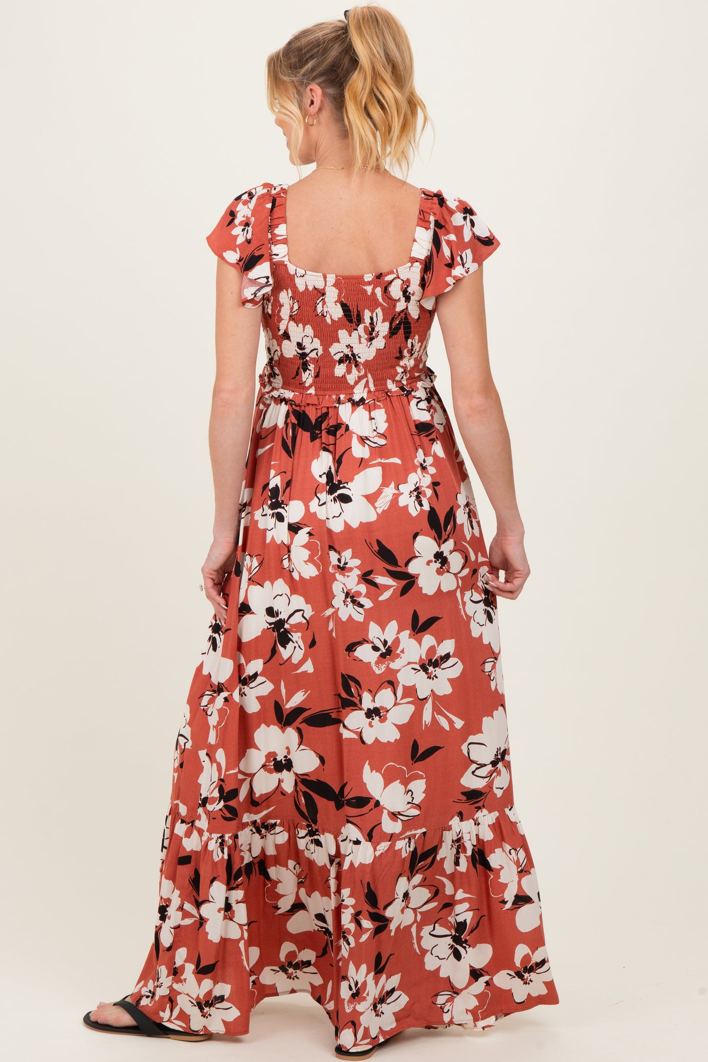 woman wearing a floral maternity maxi dress with ruffle sleeves and a smocked back, showing a baby bump