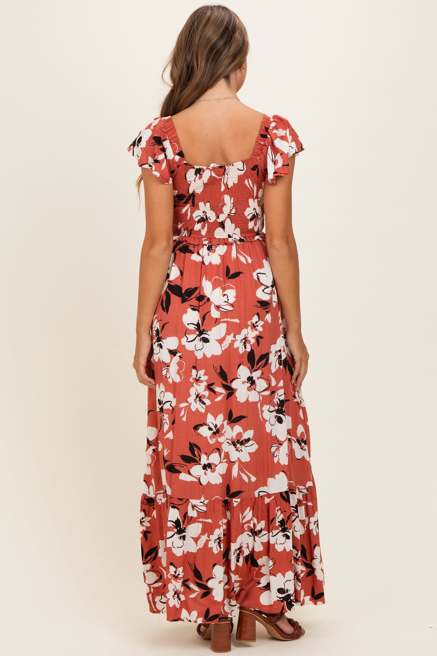 woman wearing a floral print maxi dress with ruffled sleeves and a smocked bodice, viewed from the back