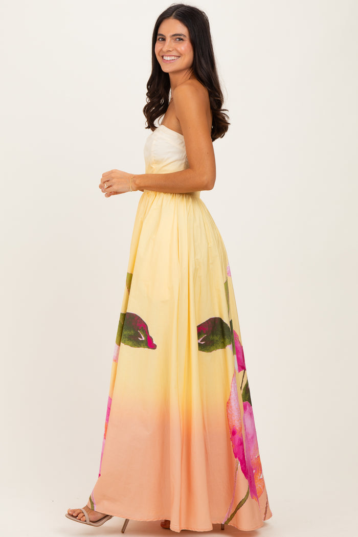 woman wearing a yellow and pink floral maxi dress with a strapless design and a flowy skirt