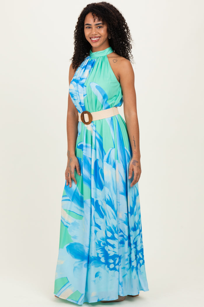 woman wearing a blue and green floral maxi dress with a halter neckline and a belt at the waist