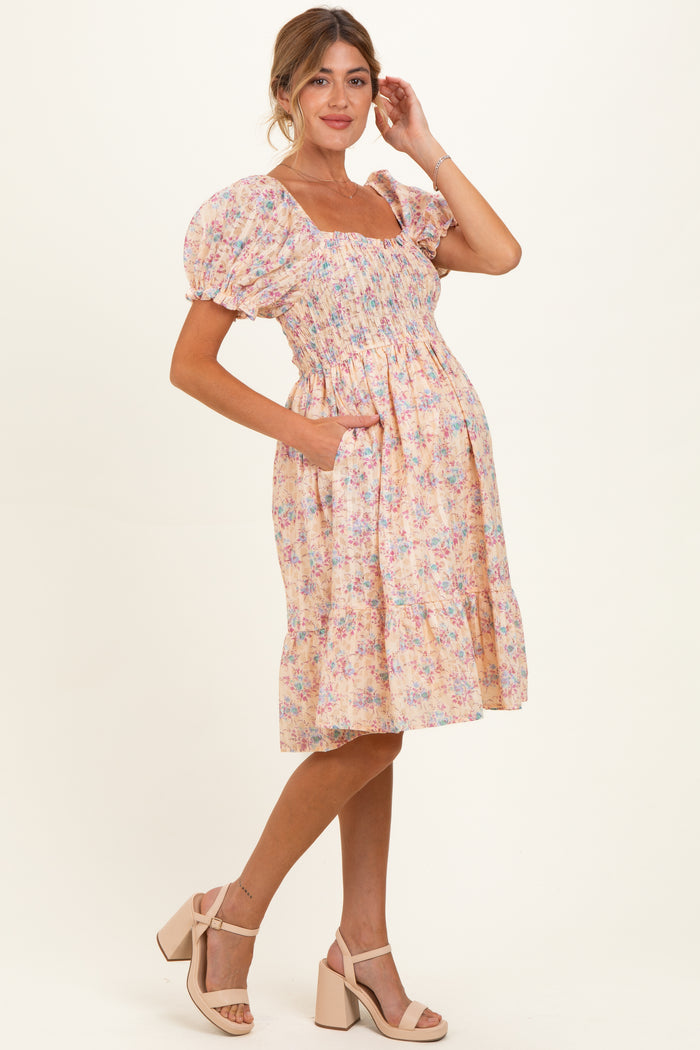woman wearing a floral pink puff sleeve maternity dress with pockets and a visible baby bump