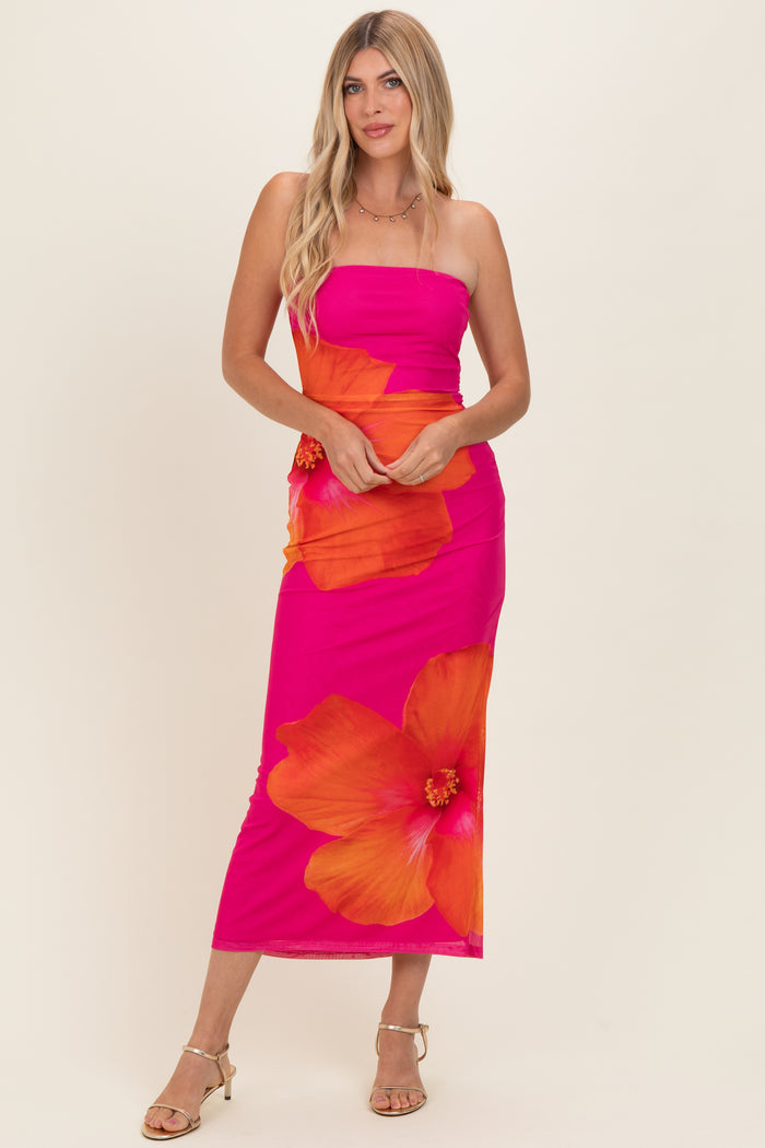 woman wearing a bright pink strapless maxi dress with large orange hibiscus flowers