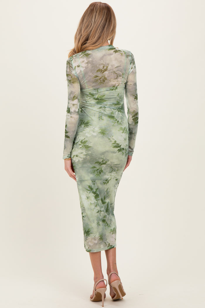 woman wearing a green floral print maternity dress with long sleeves and a fitted silhouette