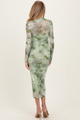 woman wearing a green floral print maternity dress with long sleeves and a fitted silhouette