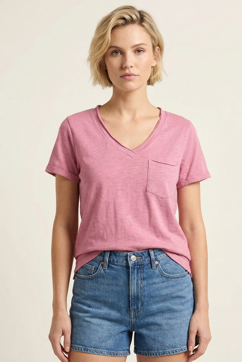 woman wearing a pink v-neck t-shirt with a pocket and high-waisted denim shorts