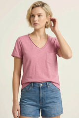 woman wearing a pink v-neck t-shirt with a chest pocket and blue denim shorts