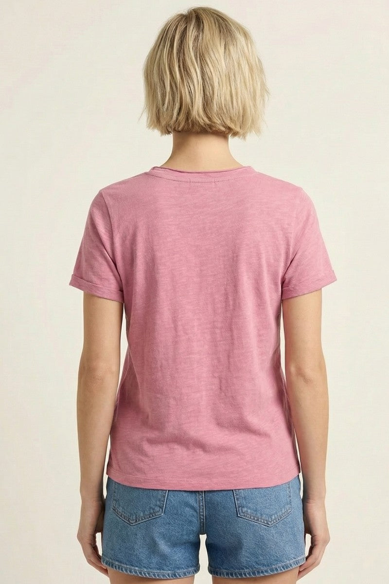 woman wearing a pink short sleeve t-shirt and denim shorts, viewed from the back