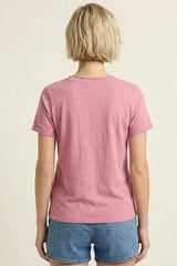 woman wearing a pink short sleeve t-shirt and denim shorts, viewed from the back