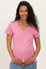 woman wearing a pink short sleeve maternity top with a pocket and holding her baby bump