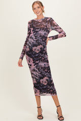 woman wearing a sheer long sleeve maternity dress in purple and black floral print, showing baby bump