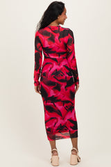 woman wearing a long sleeve red and black floral print maternity dress with a fitted silhouette