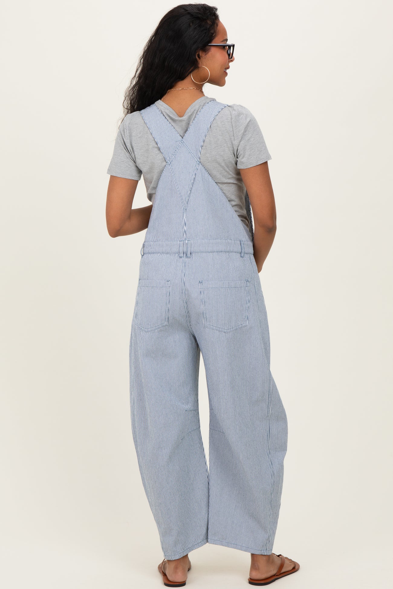 woman wearing blue and white striped maternity overalls with a gray t-shirt, viewed from the back