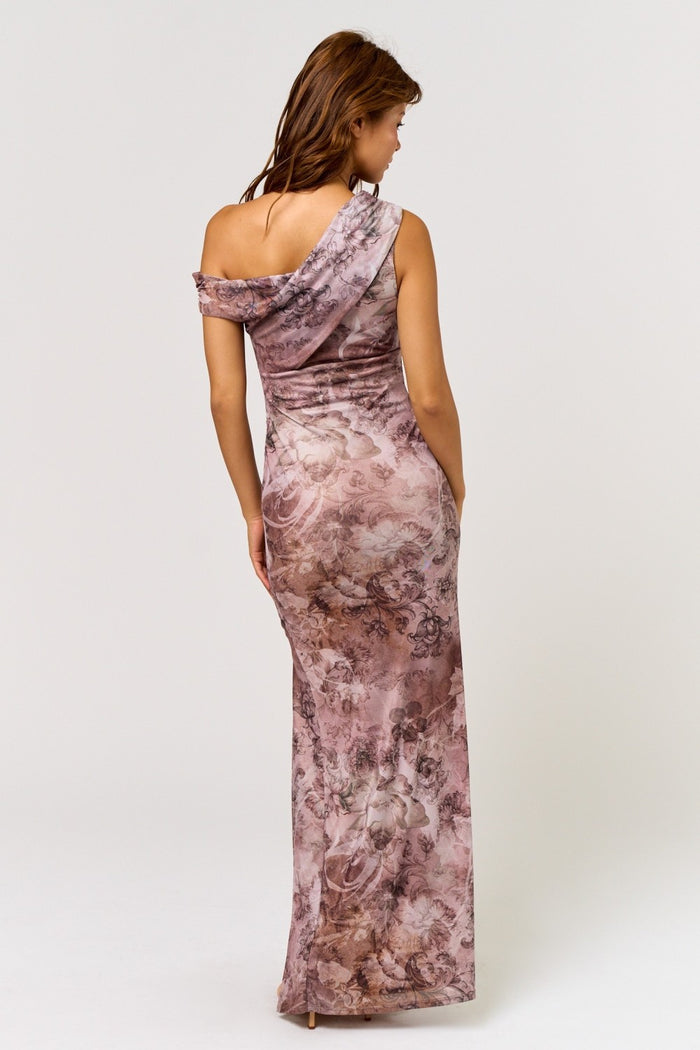 woman wearing a one-shoulder floral maxi dress in shades of pink and beige, showing a fitted silhouette from the back