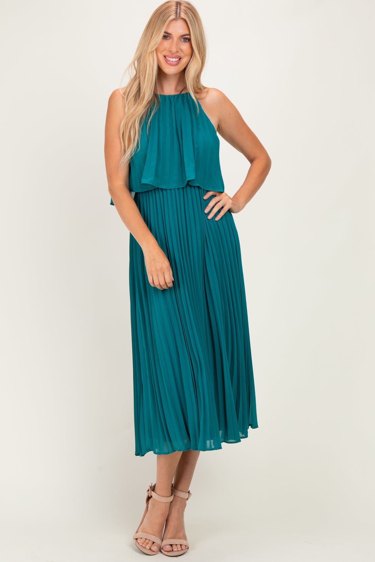 woman wearing a teal pleated midi dress with a halter neck and flowy bodice