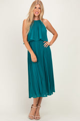 woman wearing a teal pleated midi dress with a halter neck and flowy bodice