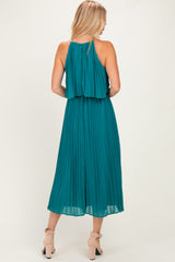 woman wearing a teal pleated midi dress with a layered back and shoulder straps