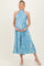 woman wearing a light blue floral pleated maternity dress with a halter neck and holding her baby bump