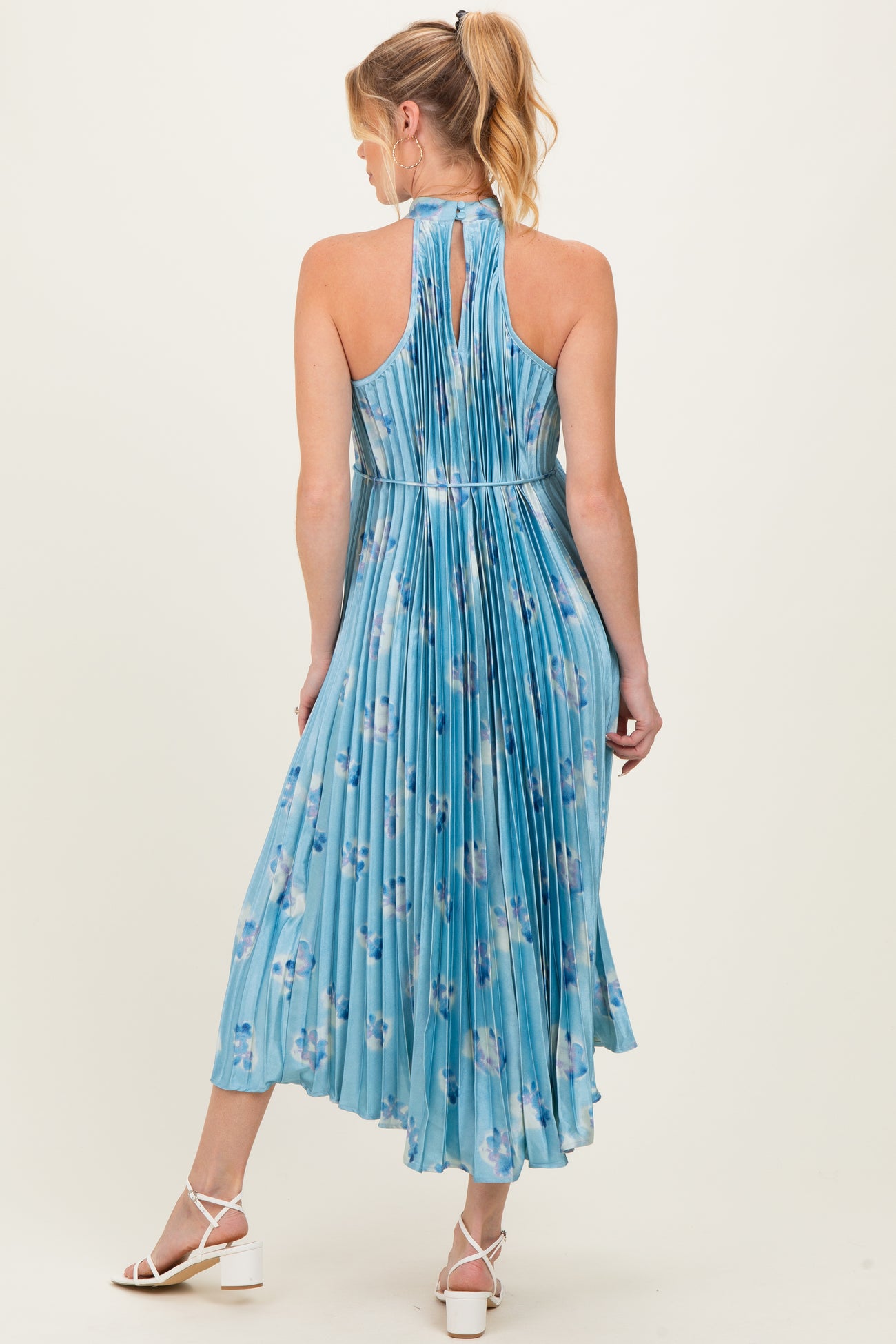 woman wearing a light blue floral maternity dress with a halter neck and pleated back design