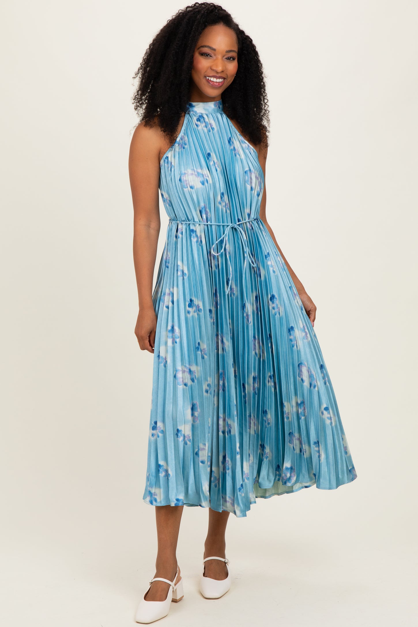 woman wearing a light blue floral pleated midi dress with a halter neck and a tie waist detail