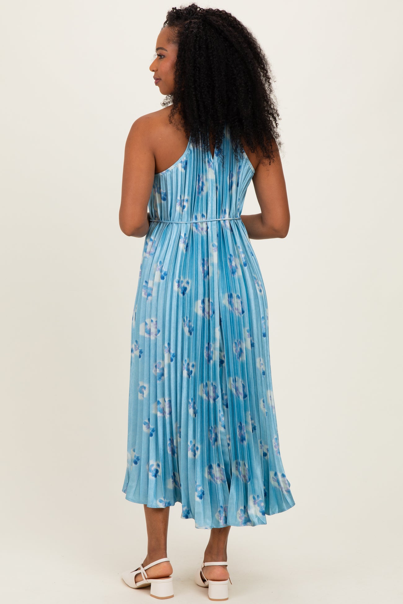 woman wearing a light blue floral midi dress with a pleated back and spaghetti straps