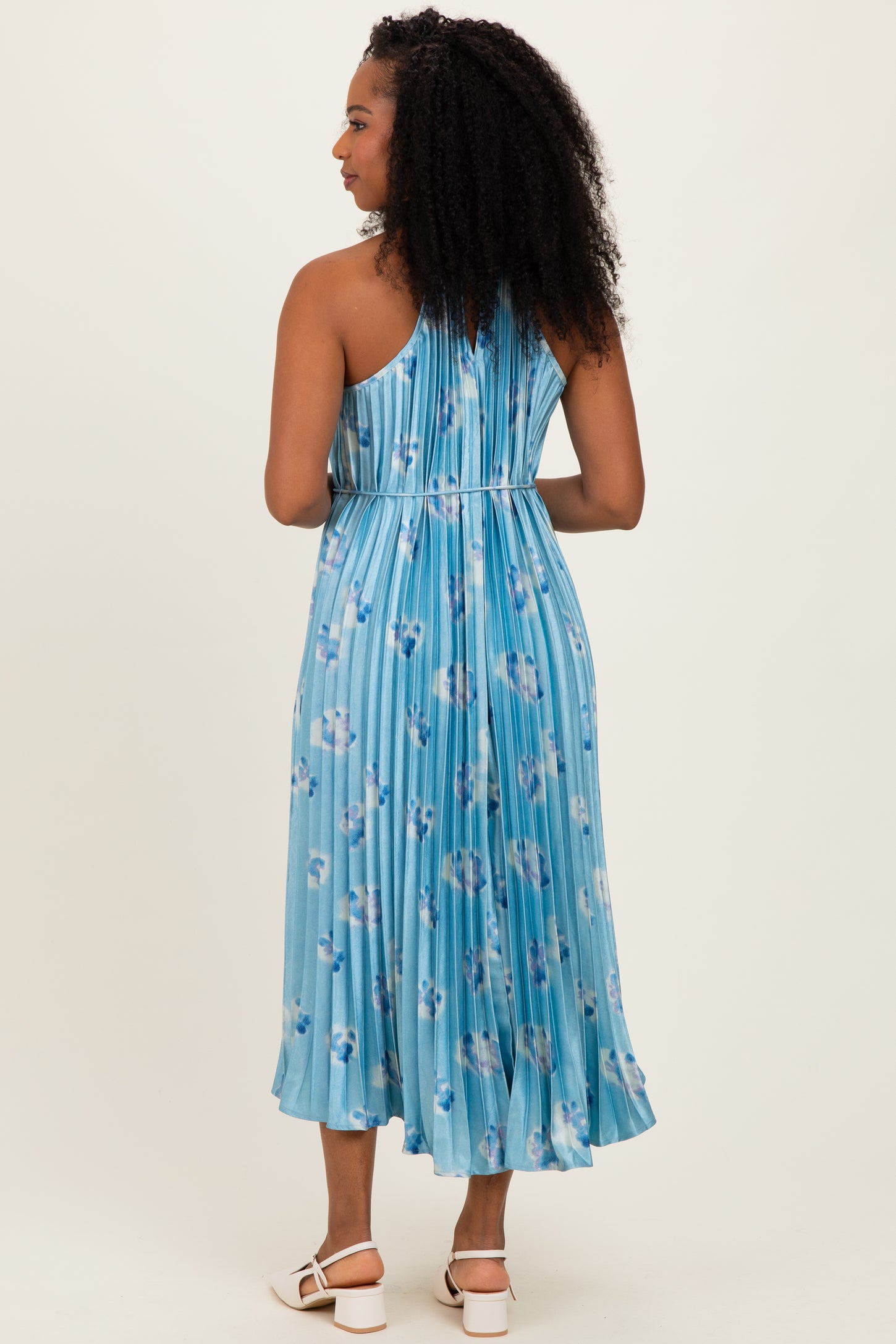 woman wearing a light blue floral midi dress with a pleated back and spaghetti straps