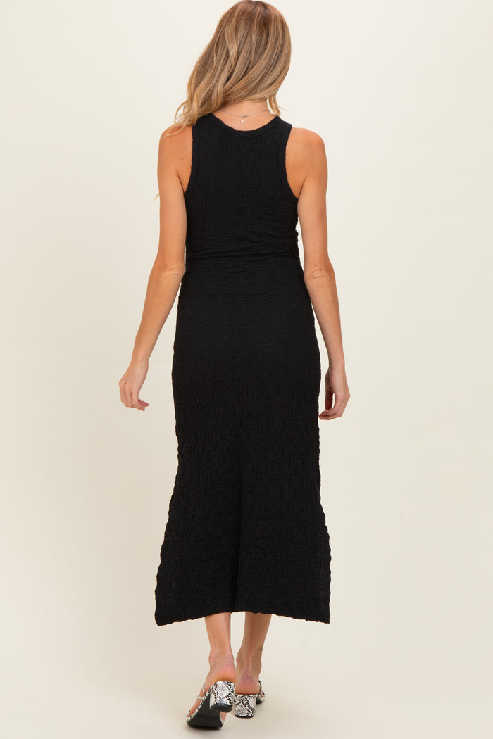 woman wearing a black maternity maxi dress, fitted style with a textured fabric, viewed from the back