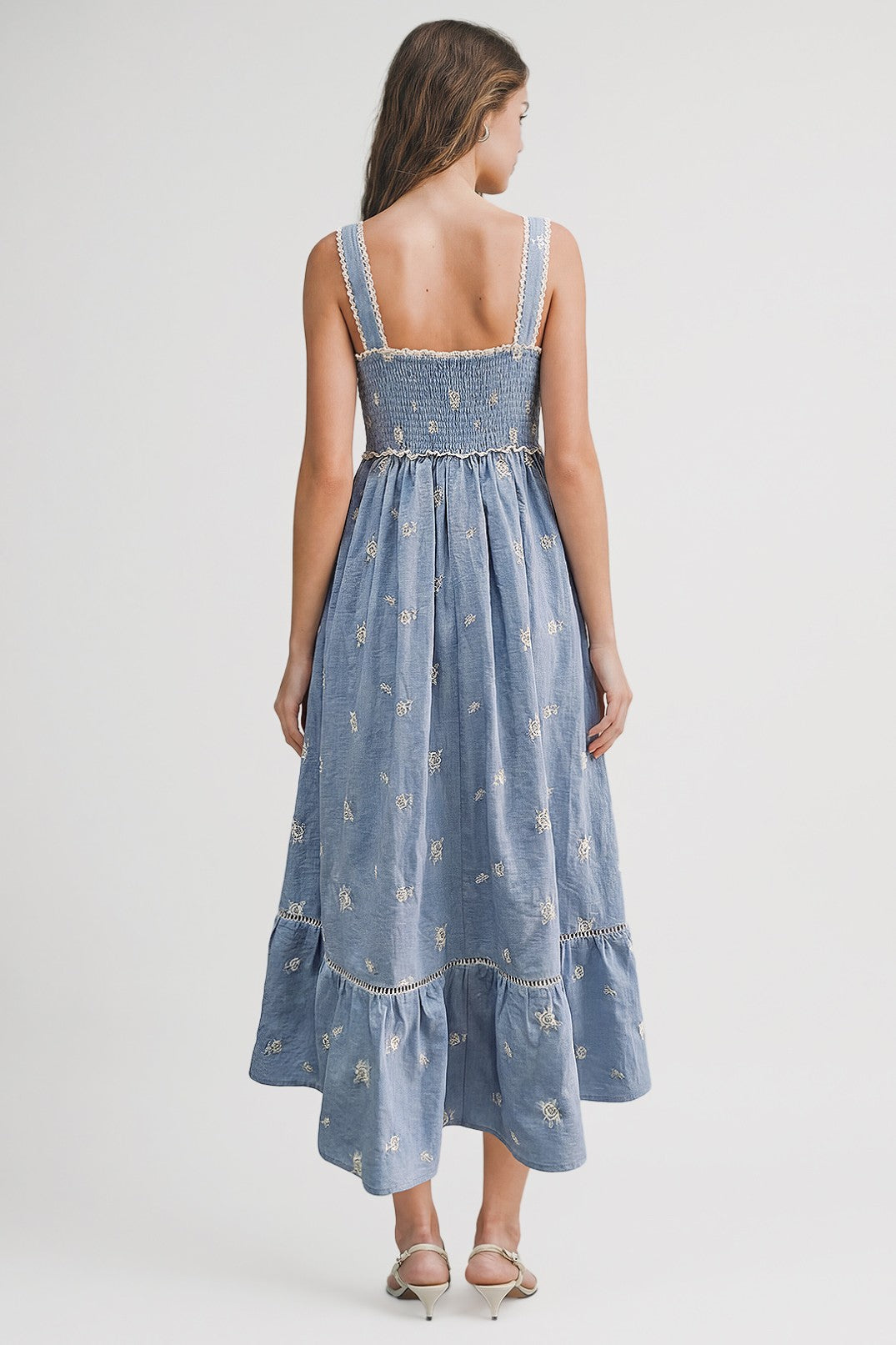 woman wearing a blue embroidered maxi dress with a smocked back and tiered skirt, viewed from the back