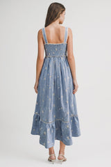 woman wearing a blue embroidered maxi dress with a smocked back and tiered skirt, viewed from the back