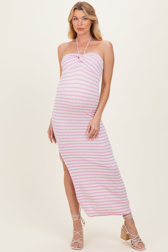 woman wearing a pink and white striped maternity maxi dress with a halter neckline and side slit, showing off her baby bump