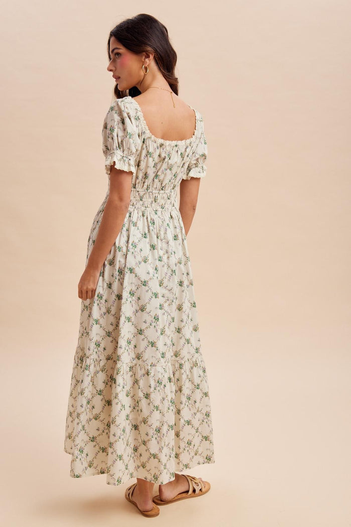woman wearing a floral print maxi dress with puff sleeves and a smocked waist, standing against a neutral background