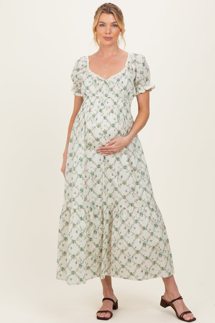 woman wearing a floral printed maternity maxi dress with puff sleeves and holding her baby bump
