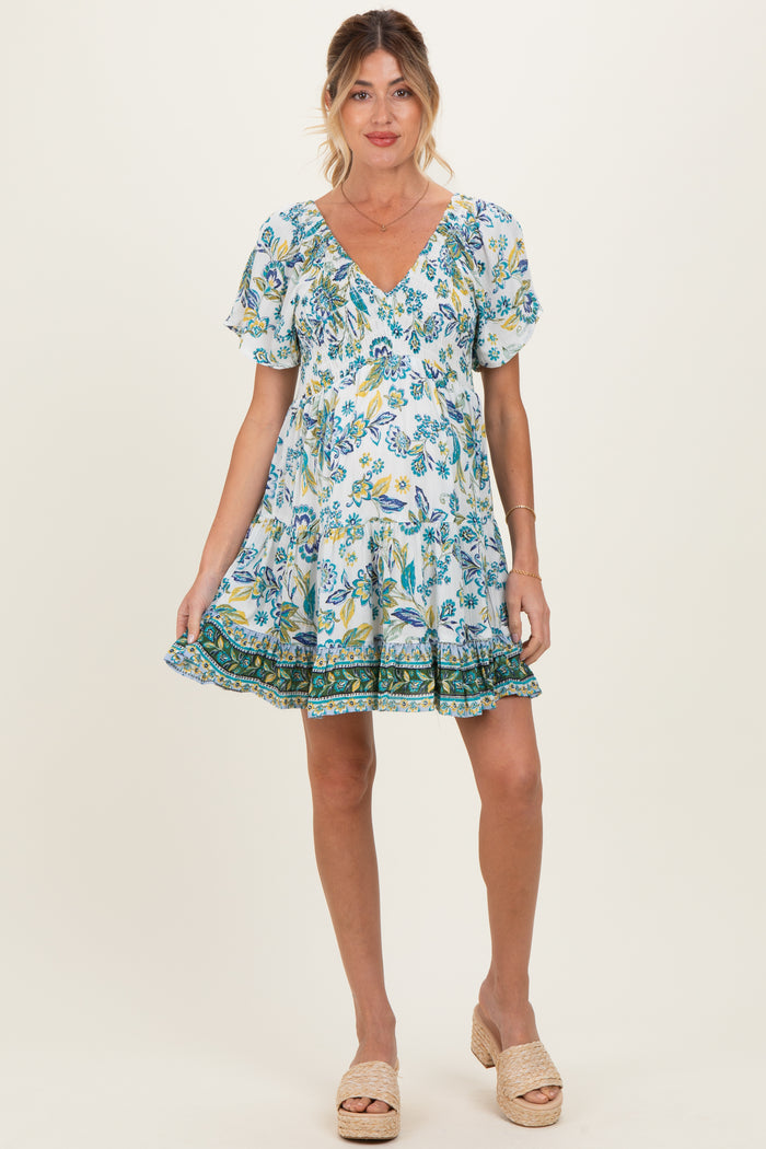 woman wearing a floral print maternity dress with short sleeves and a ruffled hem, showing her baby bump