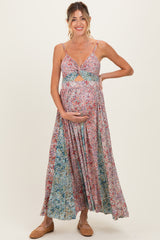 woman wearing a floral maternity maxi dress with a cutout detail and holding her baby bump