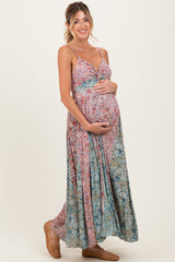 woman wearing a floral maternity maxi dress with a baby bump, featuring adjustable straps and a flowy silhouette
