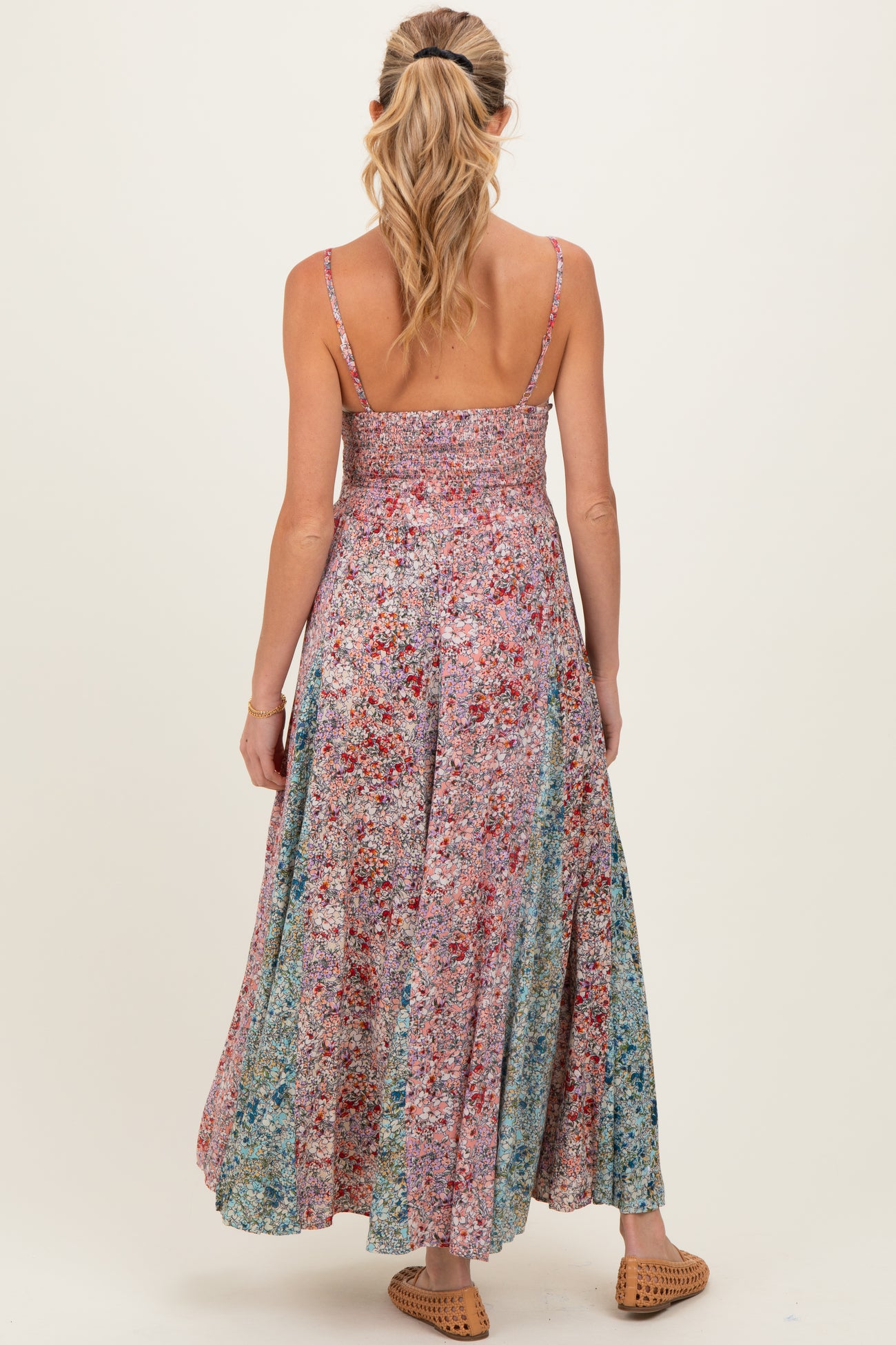 woman wearing a multicolored floral maternity maxi dress with a smocked bodice and adjustable straps, viewed from the back