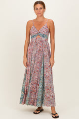 woman wearing a floral maxi dress with a cutout under the bust and spaghetti straps, standing in flip-flops