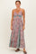 woman wearing a floral maxi dress with a cutout under the bust and spaghetti straps, standing in flip-flops