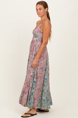 woman wearing a colorful floral maxi dress with a fitted bodice and flowy skirt, standing sideways